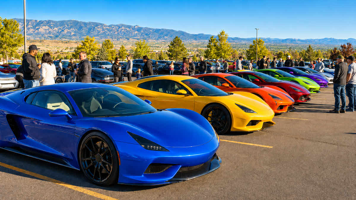 Colorful supercars and exotic cars lined up at a Denver Cars and Coffee meet with attendees and Colorado mountains in the background.